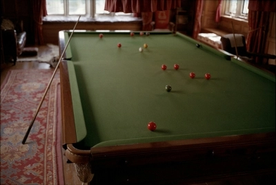 A billiards table with cues and balls in a vintage room with patterned carpet.