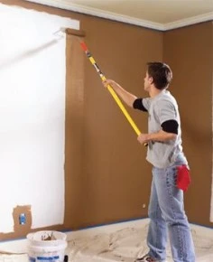 Painter with roller brush painting the wall brown