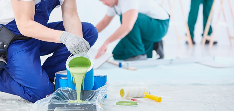 Person pouring paint into a container.