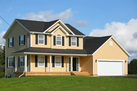 Yellow, two story home with attached garage, black roof and black shingles  