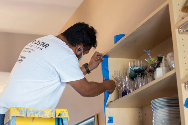 Five Star Painting of Brandon and Riverview interior painter applying painters tape to a shelving unit.