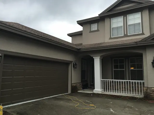 A two story home painted brown with a dettached garage