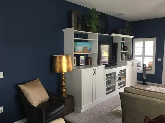 A living room painted blue with a white bookcase and furniture