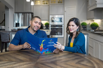 Man and woman sitting at kitchen table reading a Five Star Painting brochure.