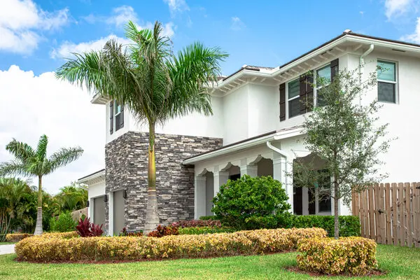 two story house with brick work and manicured lawn.