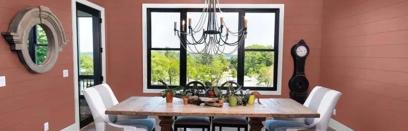 Dining room in wall colors of terracotta, light terracotta and white overlooking a yard.