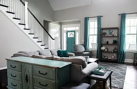 white living area with teal accents on drapes and door.