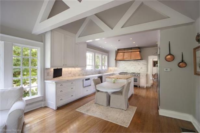Open floor plan kitchen with white cabinets and light hardwood floors.