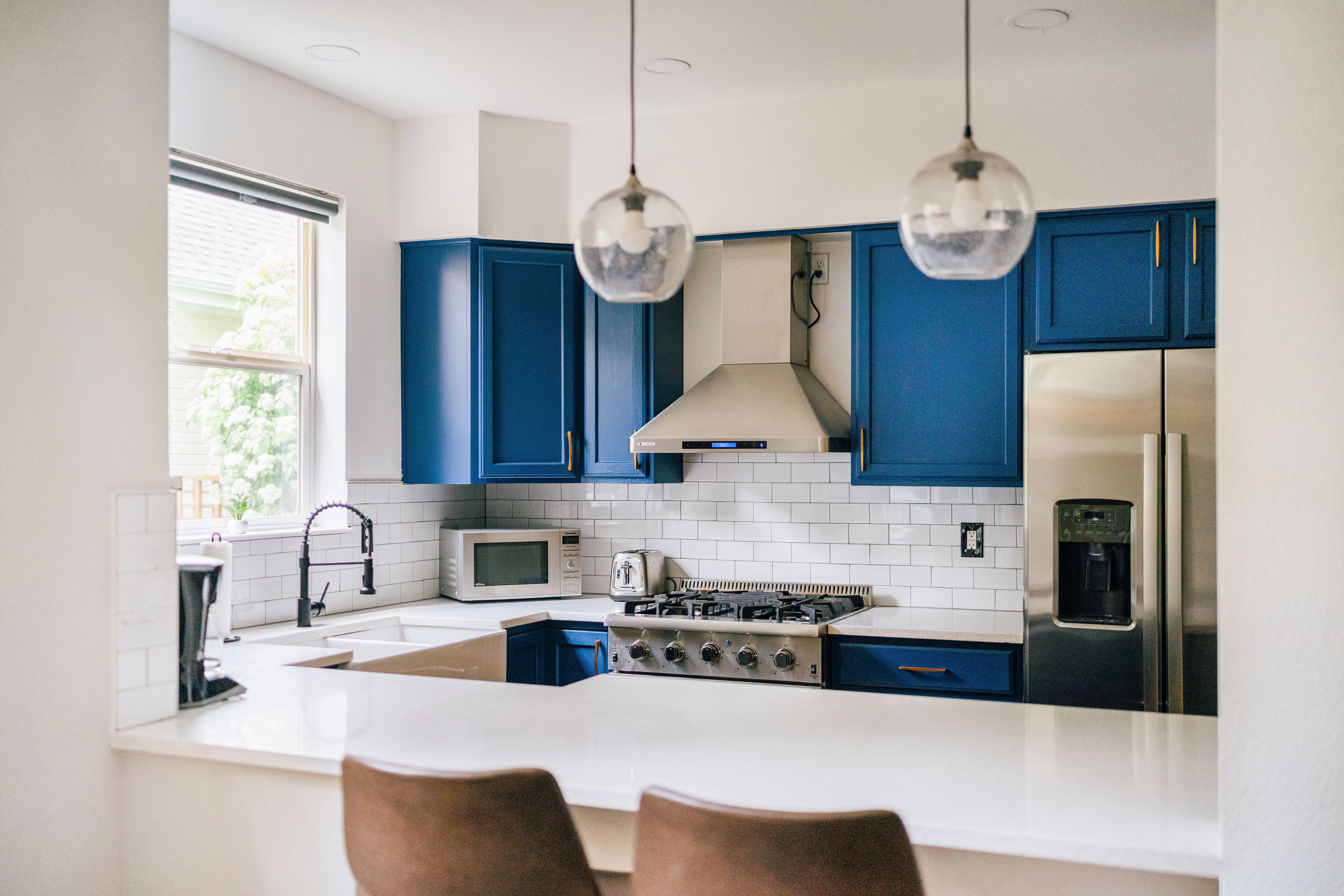 Modern farmhouse kitchen with bar wall design, cobalt blue cabinets, white walls and backsplash.