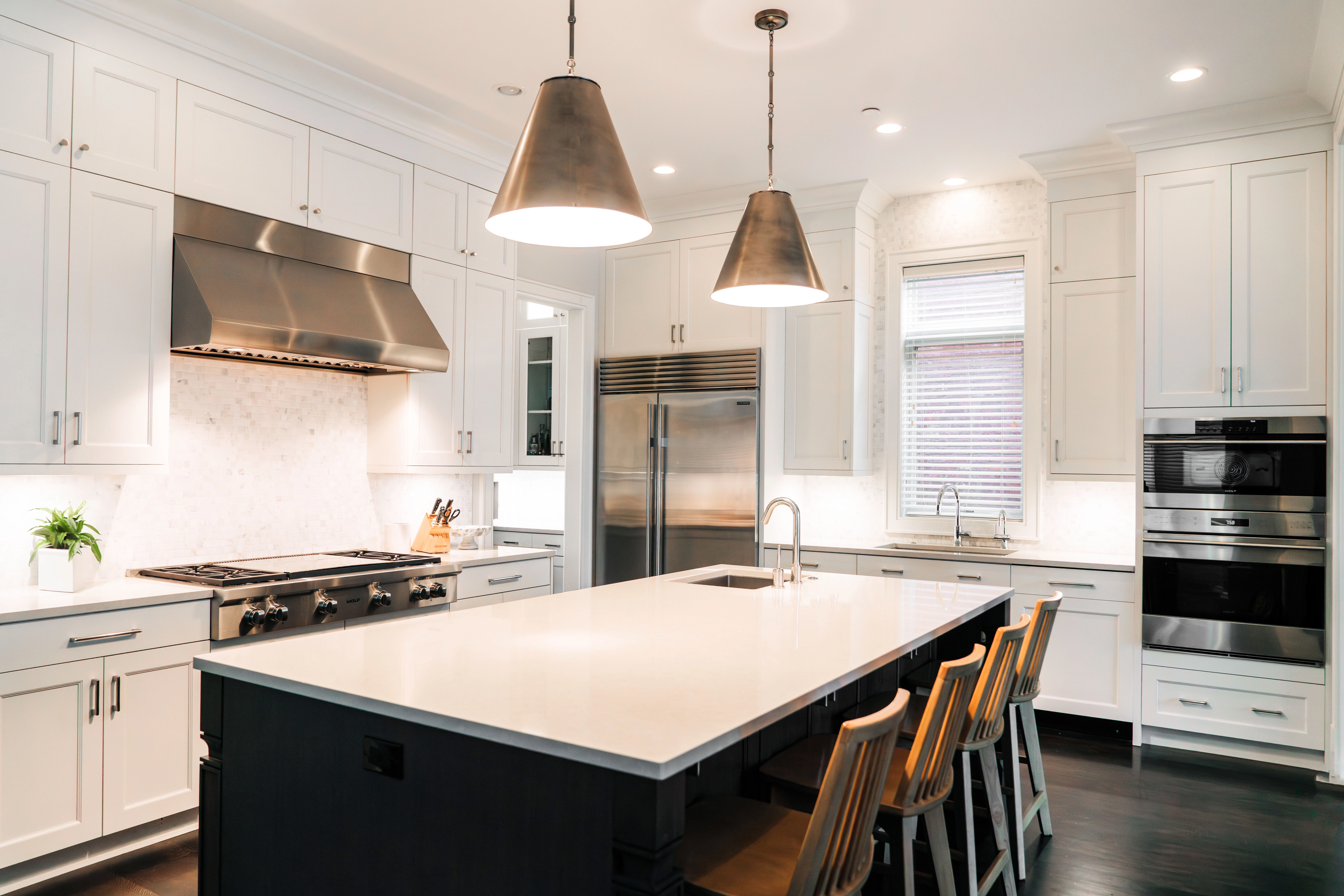 Kitchen with white cabinets, crown molding, stainless steel appliances, and island painted black.