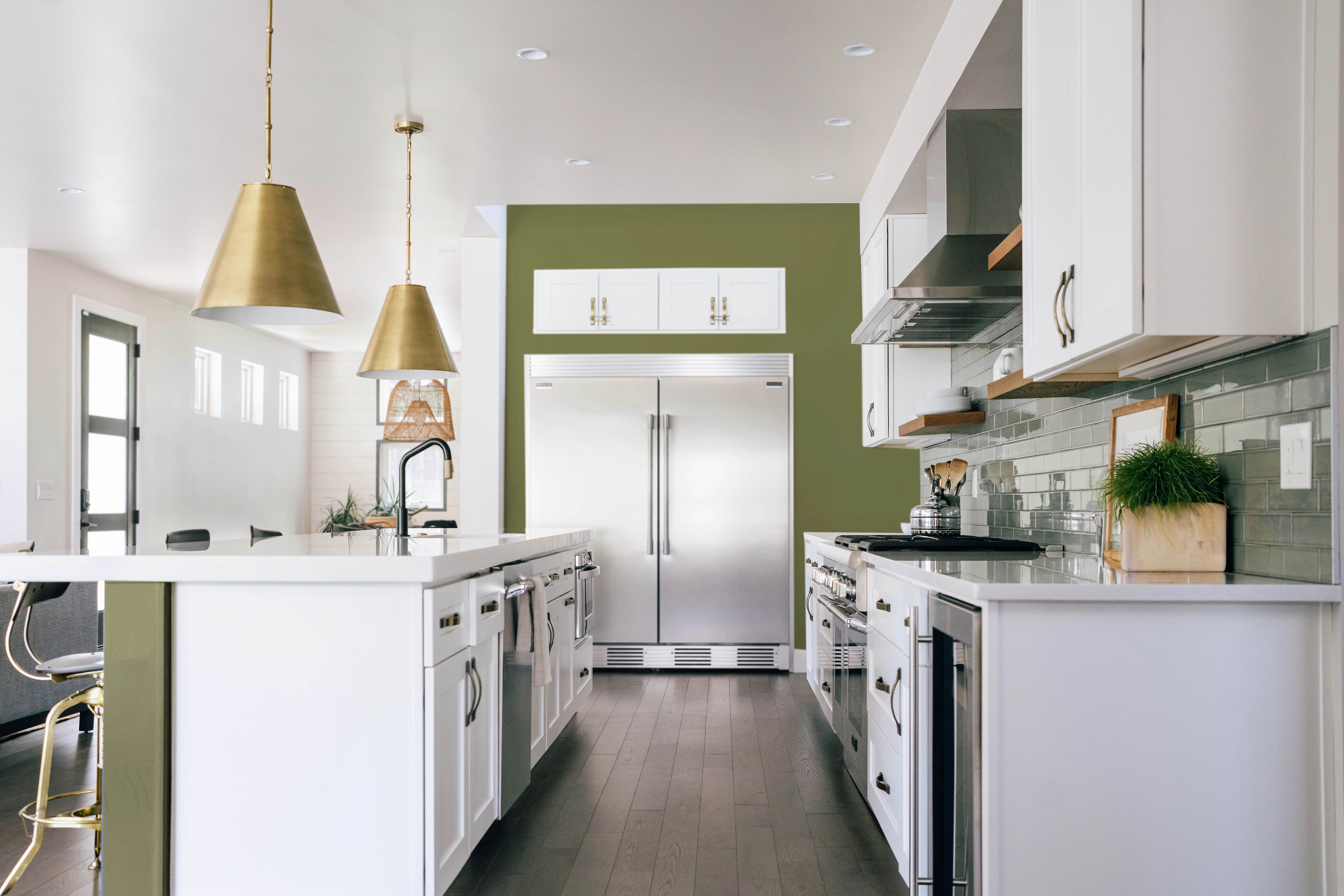 Modern white kitchen with mossy green painted accent wall and green tile backsplash. 