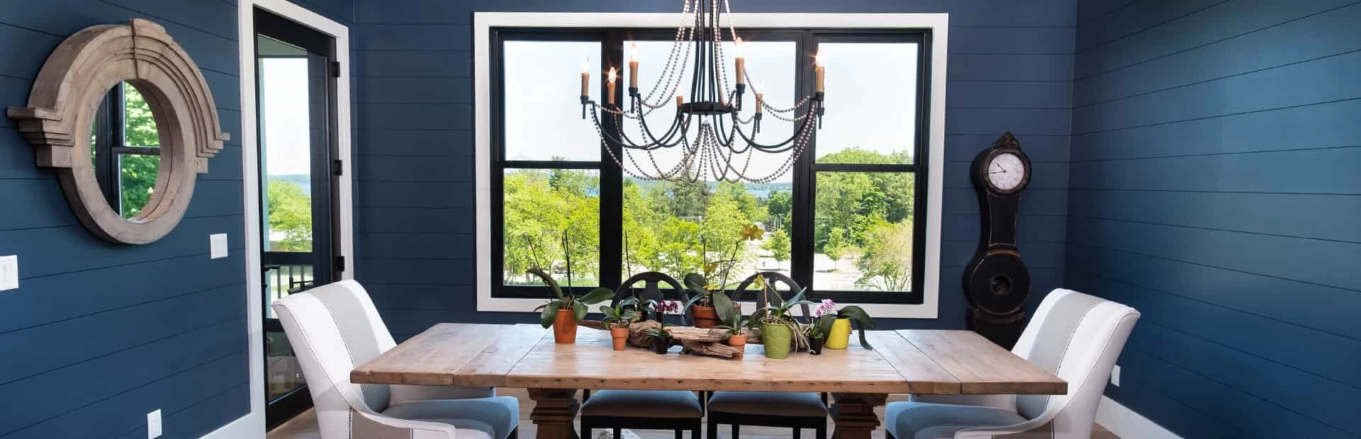 Dining room in original wall colors of dark blue overlooking a yard.