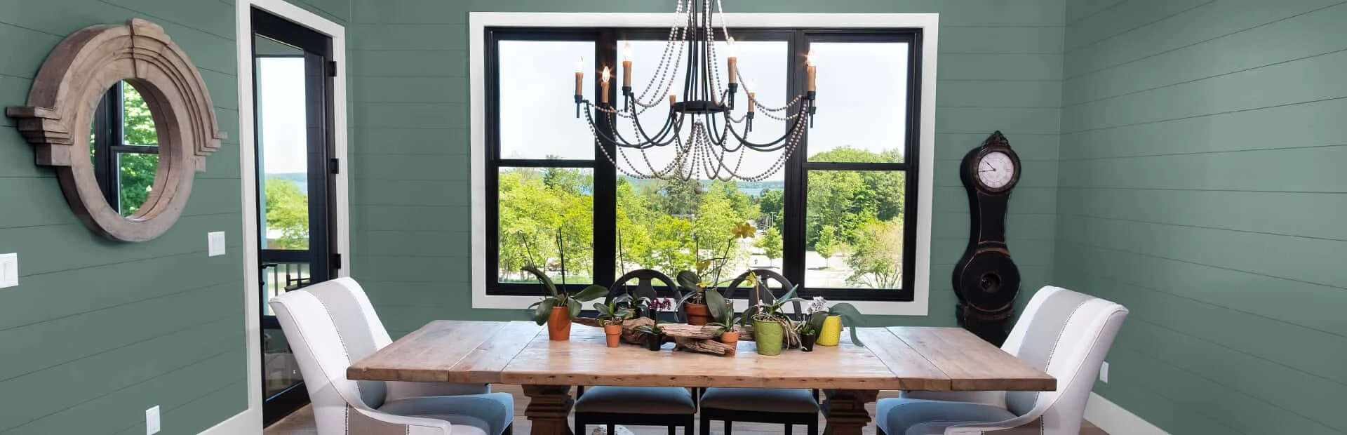 Dining room in wall colors of light forest green, light tan and white overlooking a yard.