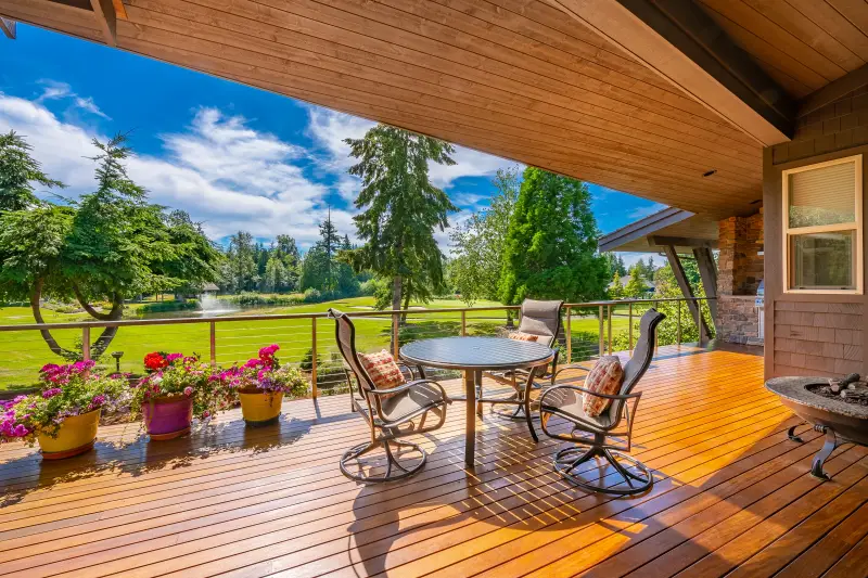 beautiful stained deck overlooking backyard with blue sky and green trees