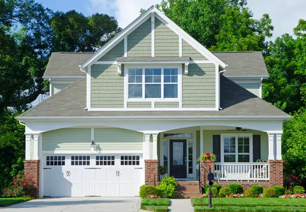 Two story residential home with garage painted green with white trim.