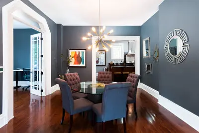 Dining room with blue walls and starburst chandelier above dining table.