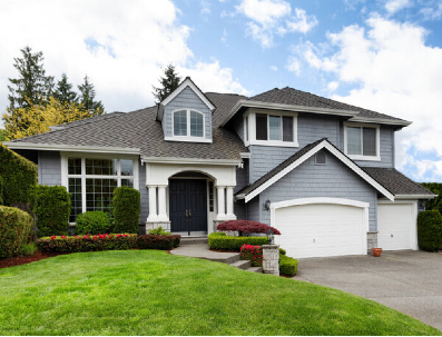 Landscaped residential two story home with gray siding and white trim.