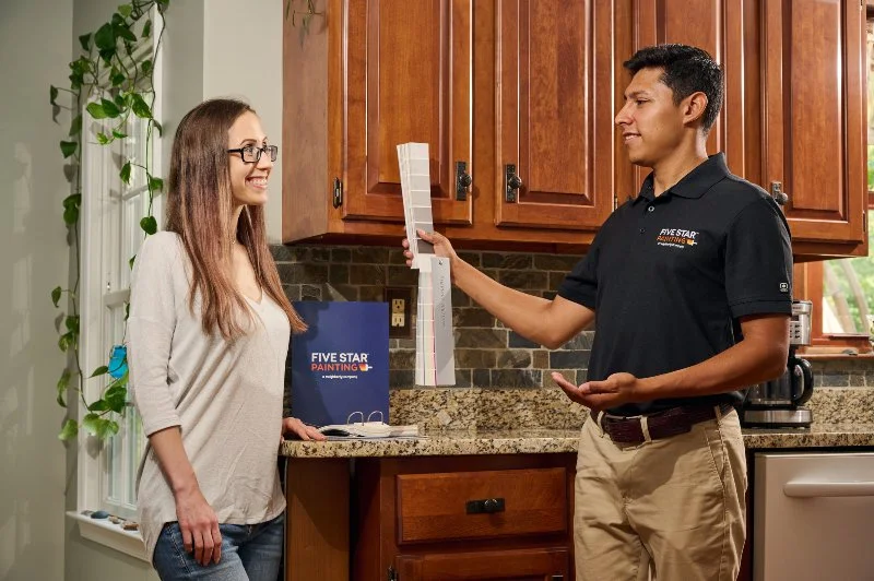 A Five Star Painting estimator showing a customer color swatches for her cabinets 