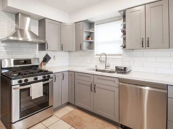 Large kitchen with wood floors, an island in the middle and off white cabinets.