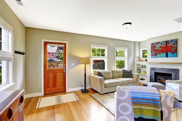 A warm living room with a red door, fireplace, furniture and colorful blanket over a chair