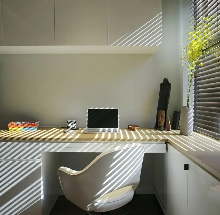 An office with desk, chair and computer next to a window
