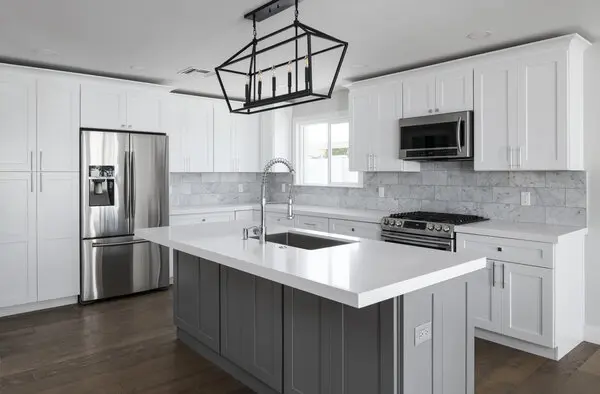 Large kitchen with wood floors, an island in the middle and off white cabinets.