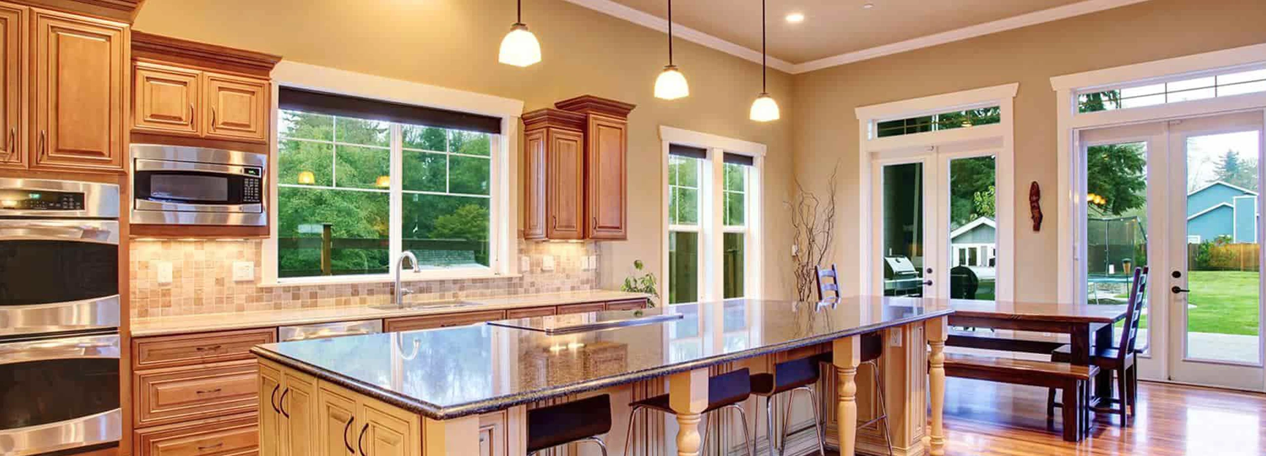 Brown contemporary kitchen with island with windows and french doors leading to backyard