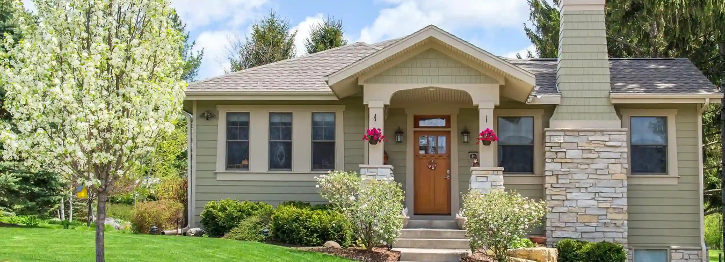 Craftman style home surrounded by greenery.