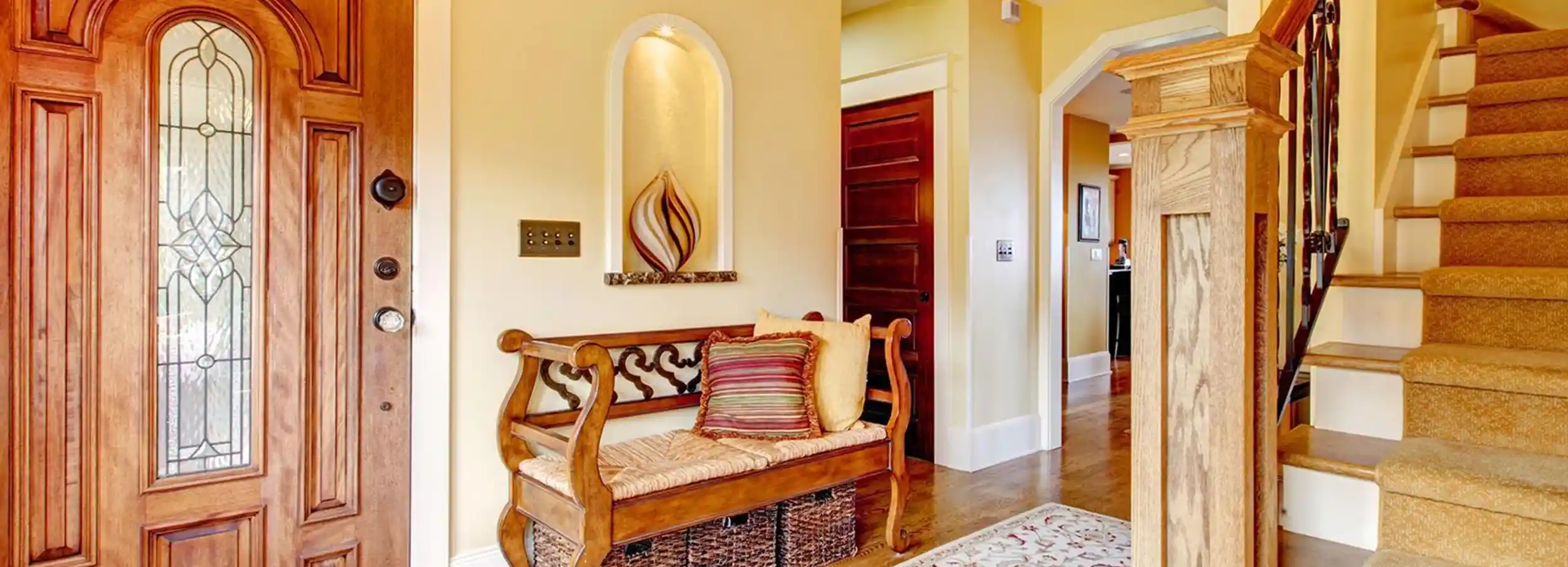 Entryway of home with staircase and traditional wood bench.