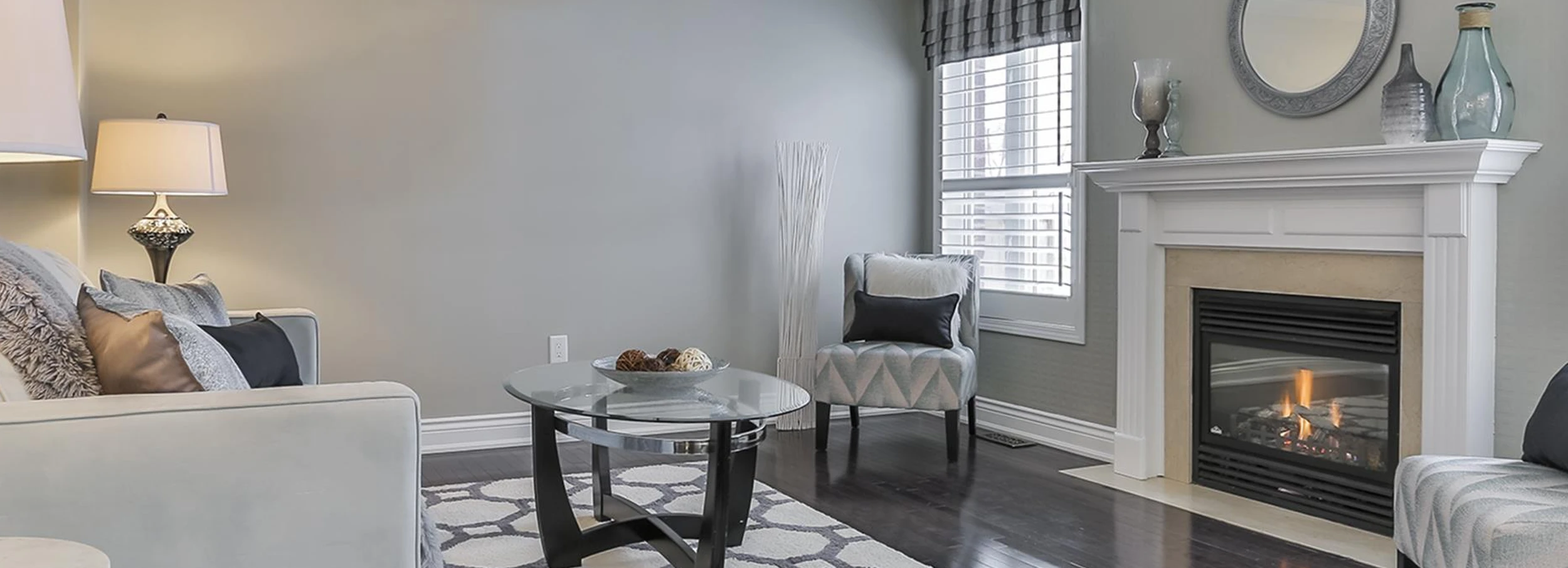 Sitting room with white walls and white couch in front of lit fireplace.