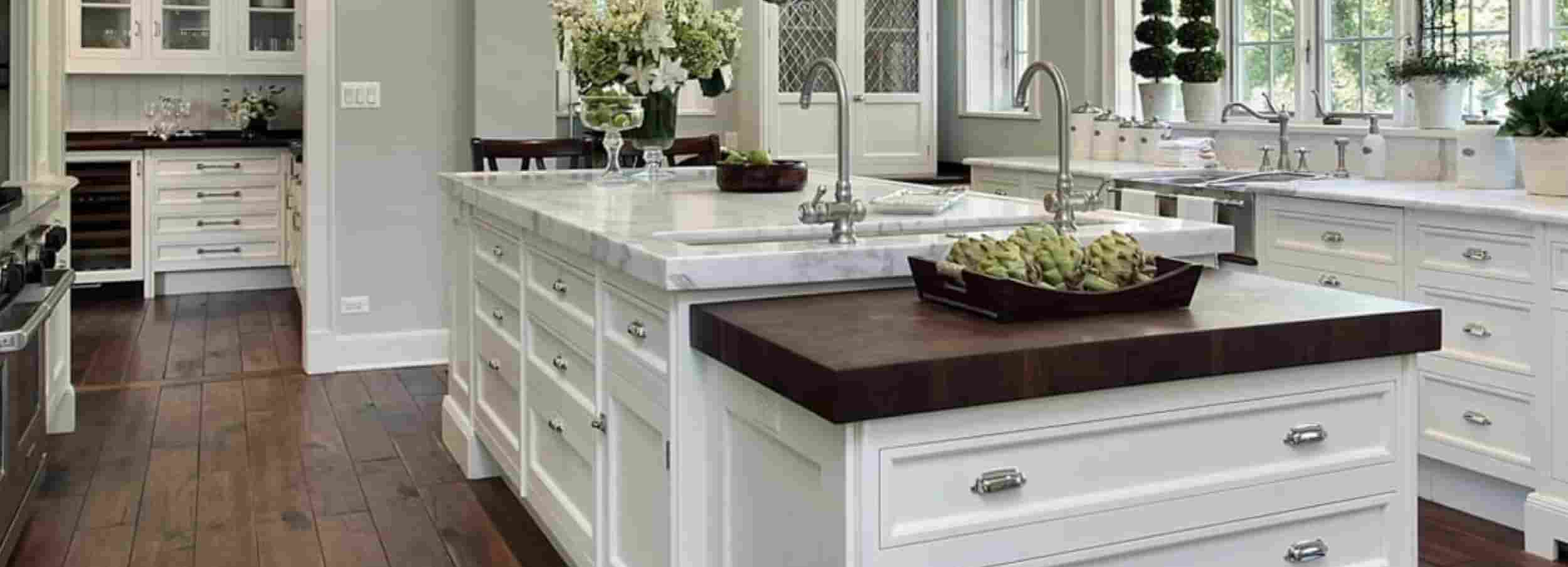 Modern, bright white kitchen with island and dark hardwood floors.