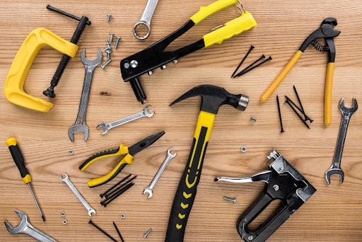 various hand tools on a wood background