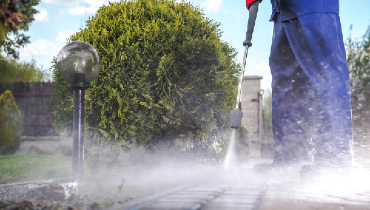 Service professional pressure washing a wooden deck.
