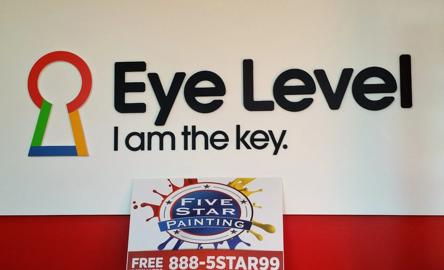 "Photo of Eye Level logo on a wall above a Five Star Painting sign"