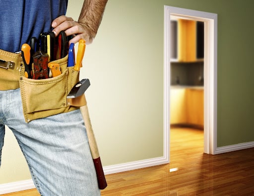 handyman in a toolbelt standing in house