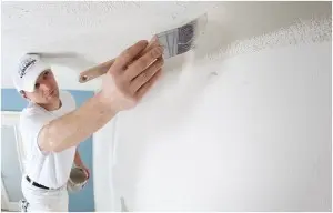 technician in white painting wall