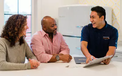 A Five Star Painting estimator reviewing interior painting project details with two homeowners.