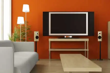 A living room painted orange with a large television and furniture.