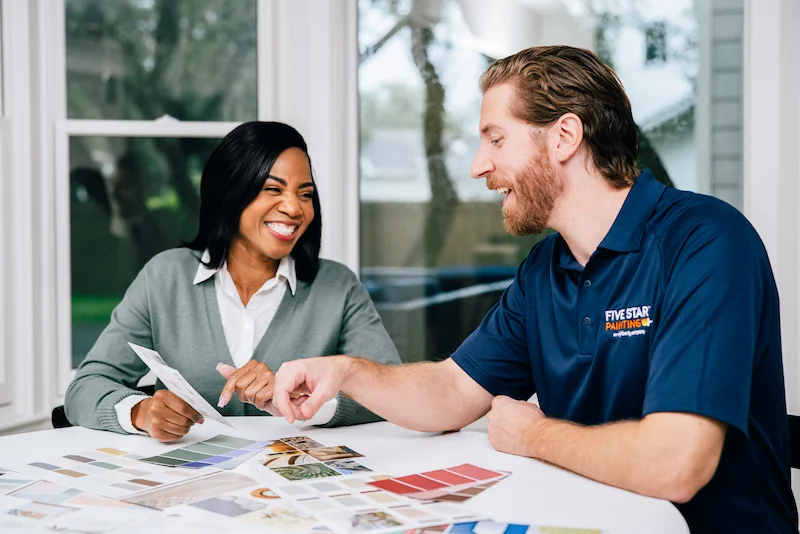 Smiling female client and painting technician reviewing paint swatches. 