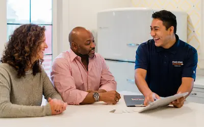  A male FSP technician sitting a table speaking with customers about services.