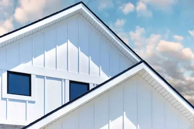 Home with siding painted white with rooftop set against blue sky.