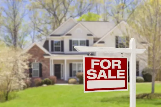 For Sale sign with residential home in background.