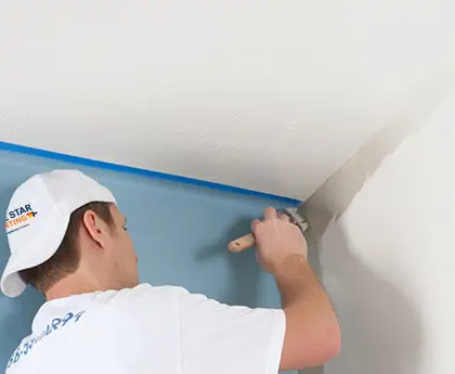 Painter applying gray paint to a wall.