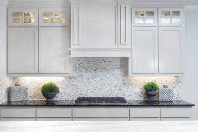 gorgeous cream kitchen cabinets with backsplash, stove, and dark counter