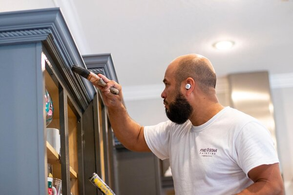 Five Star Painting of Tampa Bay painter carefully painting cabinets a trendy, modern grey