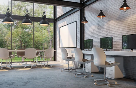 A modern industrial large room with a conference table and multiple office chairs, filing cabinets and computers. 