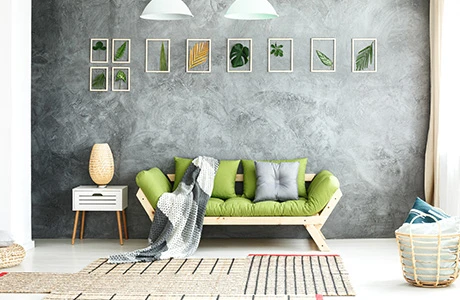 A modern room with a futon, white floor and a grey painted wall with a faux finish styling.  