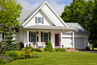 white two story cottage with cozy front porch.