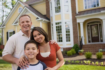 Happy family standing in front of their freshly painted home.