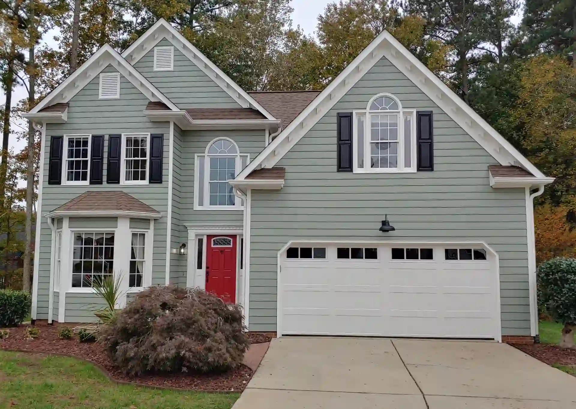 Exterior of a gray painted house with garage and a red painted door.